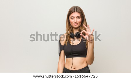 Young fitness russian woman cheerful and confident doing ok gesture