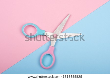 Open pink and blue scissors on the pink and blue background (minimal concept)