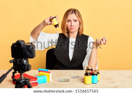 Isolated view of sad blonde nutritionist showing empty bottle with her health supplement, forgot to buy new one, purses lips and frowns, displeased and upset expression. Studio shot.