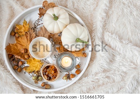 Large wooden serving with a Cup of coffee with brown sugar, burning candles .Seasonal decoration of foliage and pumpkins .Autumn