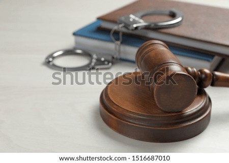 Judge's gavel, handcuffs and books on white wooden background. Criminal law concept