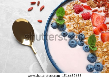 Smoothie bowl with goji berries and spoon on grey table, closeup
