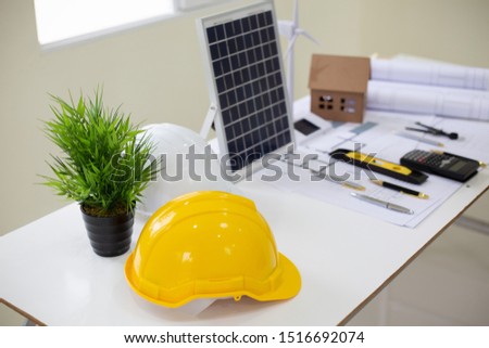 Desk of Architectural working solar panel home project in construction site,With drawing equipment concept.
