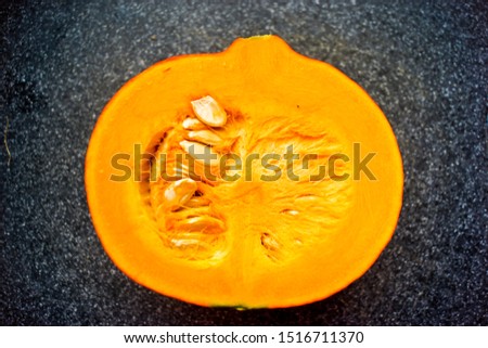 An orange pumpkin on a dark cutting board