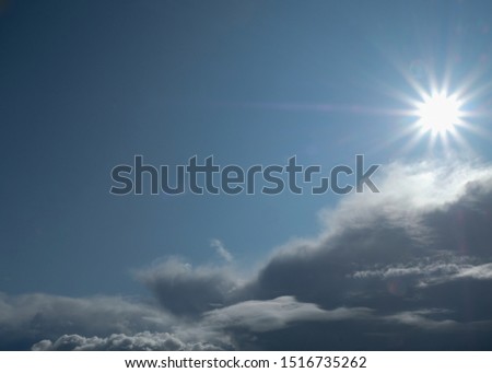 The sun and clouds on the blue sky. Cloudy weather with cumulus, dark clouds. Autumn day. A strong wind blows, the pressure is low, the threshold of rain.
