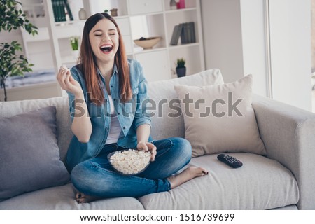 Photo of amazing lady watching favorite humorous tv show eating popcorn laughing out loud sitting comfy sofa wearing jeans clothes apartment indoors Royalty-Free Stock Photo #1516739699