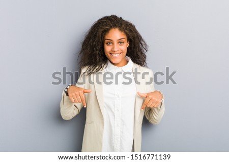 Young african american business woman points down with fingers, positive feeling.