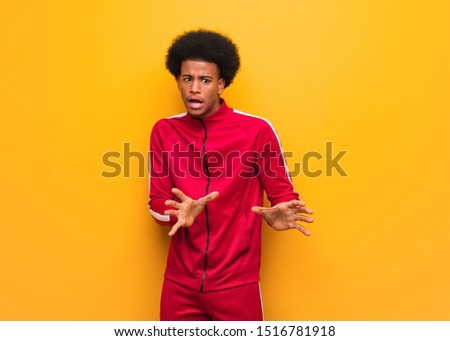 Young sport black man over an orange wall rejecting something doing a gesture of disgust