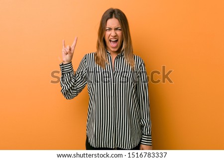 Young authentic charismatic real people woman against a wall showing a horns gesture as a revolution concept.
