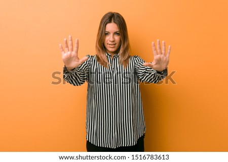 Young authentic charismatic real people woman against a wall showing number ten with hands.