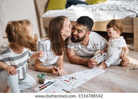 beautiful mother kissing her husband while having art lesson with her children, close up photo.
