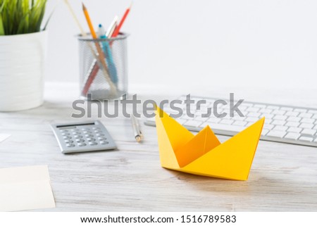 Businessman workspace with office desk and yellow paper ship. Marketing and advertising. Flat lay wooden table with computer keyboard and calculator. Creative project management and leadership