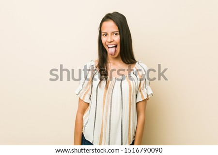 Young hispanic woman funny and friendly sticking out tongue.
