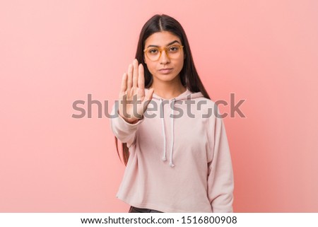 Young pretty arab woman wearing a casual sport look standing with outstretched hand showing stop sign, preventing you.