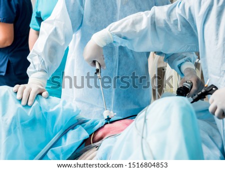 Process of gynecological surgery operation using laparoscopic equipment. Group of surgeons in operating room with surgery equipment. Medical background