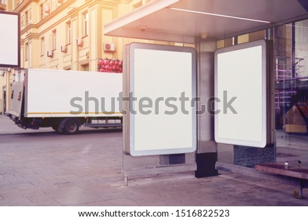 Empty billboards, advertising placeholder on a public bus stop, truck behind near house, mockup of a blank white poster.                            