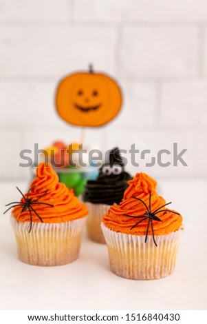 Scary or cute Halloween cupcakes of pumpkin on background, creative decoration