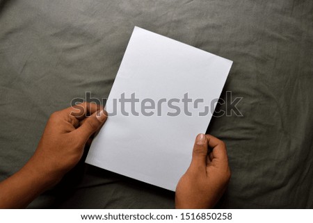 Young man hands holding blank white paper on table background