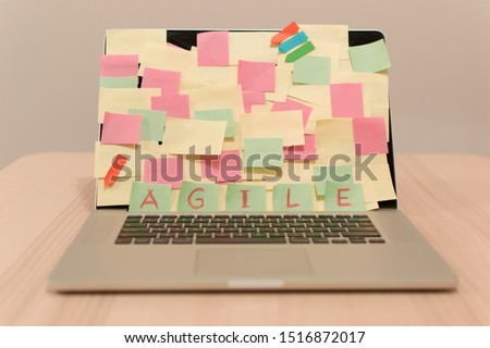 Laptop screen covered by adhesive notes, AGILE is written with adhesive notes. Kanban tool with adhesive notes is a strategy in Agile methodolgy