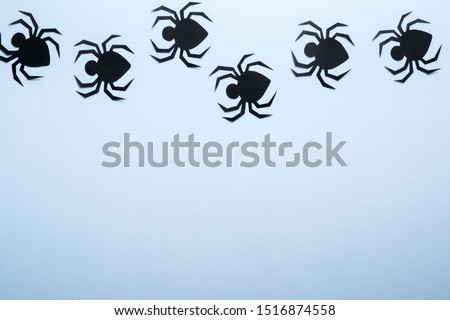 Happy halloween holiday concept. Halloween paper decorations, scary spiders on blue background. Flat lay, top view, overhead.