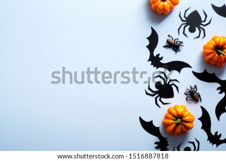 Happy halloween holiday concept. Halloween decorations, spiders, bats, pumpkins on blue background. Flat lay, top view, overhead.