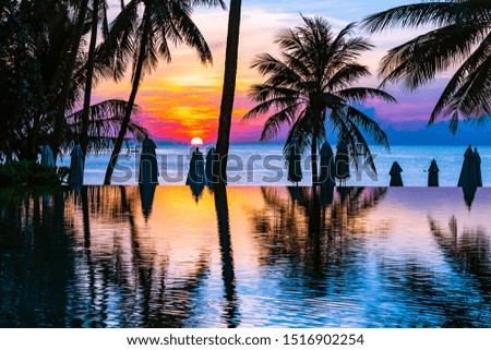 Beautiful outdoor tropical nature landscape of swimming pool in hotel resort with coconut palm tree umbrella and chair nearly sea ocean beach at sunrise time
