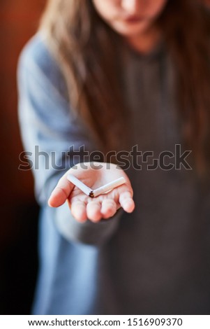 A young girl holds a broken cigarette in her hands. Concept quit smoking. Bad habit.