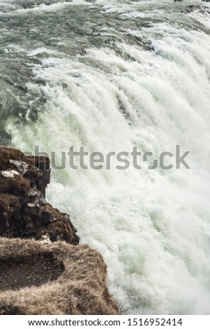 A three-step staircase of the Gullfoss waterfall on Hvita river, as pictured in  detail (water plunging into the canyon, mossy cliffs, thick spray, panorama of the rapids) 