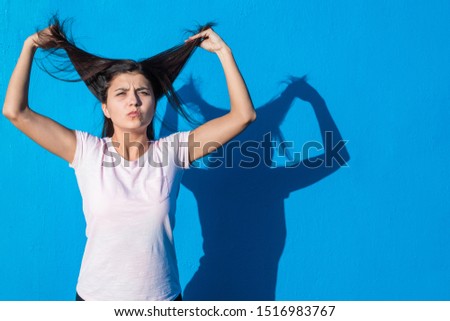 Beautiful cheerful young girl wearing casual clothes standing isolated over blue background on a sunny day. Woman feels love. People and emotions image concept with copy space.