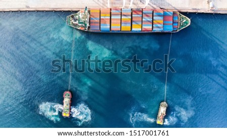 Cargo container ship was dragged by tug boat in the international terminal cargo yard port import export dealer, service logistic and transportation concept.