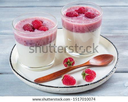 Top view of two cups of panna cotta with a teaspoon of the white rustic plate. White wooden background. Royalty-Free Stock Photo #1517010074