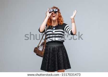red head tourist girl looks through binoculars