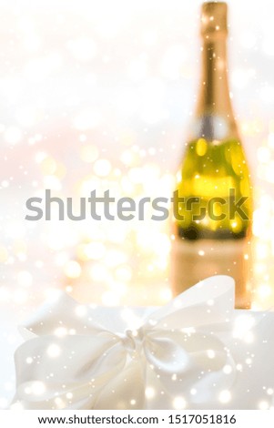Christmas time, happy holidays and luxury present concept - New Years Eve holiday champagne bottle and a gift box and shiny snow on marble background