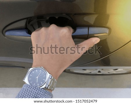 Car door handle, with a man wearing a work dress and wearing a silver watch, opening the door, taking pictures at close range