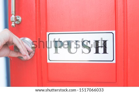 The hand is twisting the key in order to push the door into the house.