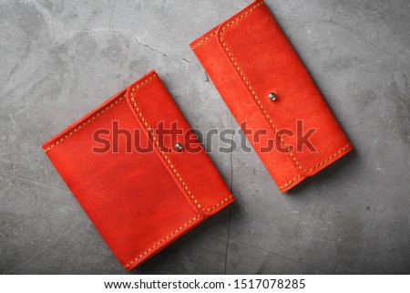 Set of two Wallets and organizer made of genuine red leather, handmade on a dark background. View from above
