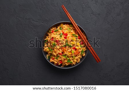 Veg Schezwan Fried Rice in black bowl at dark slate background. Vegetarian Szechuan Rice is indo-chinese cuisine dish with bell peppers, green beans, carrot. Copy space. Top view Royalty-Free Stock Photo #1517080016