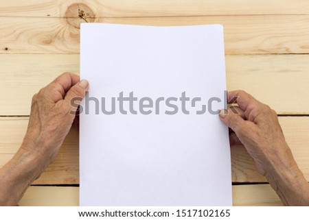 Old hands hold a blank sheet of paper. The concept of new beginnings, active old age, testament. Royalty-Free Stock Photo #1517102165
