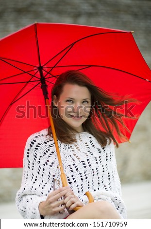 Smiling young woman with open umbrella at hand