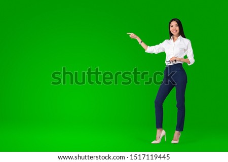 A beautiful young asian woman, anchor or tv presenter is getting filmed inside a green screen chroma key studio to create a video with removable background that can be replaced