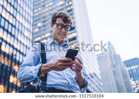 Below view of cheerful corporate employee enjoying online communication in group office chat, successful Caucasian businessman smiling while receiving funny email text on smartphone device
