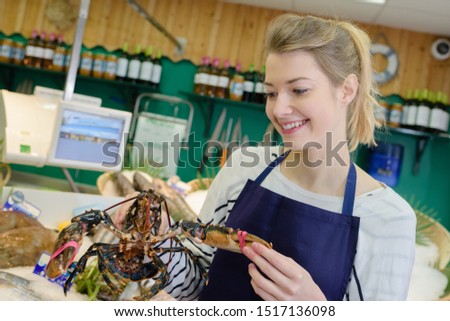 female working holding a lobster in a fish supermarket