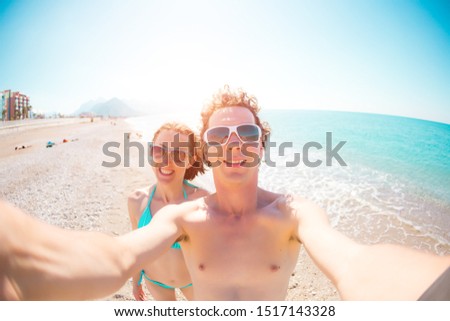 A man and a woman take a selfie. A couple is photographed on a mobile phone. Friends relax on the sea coast. Relax on the beach.