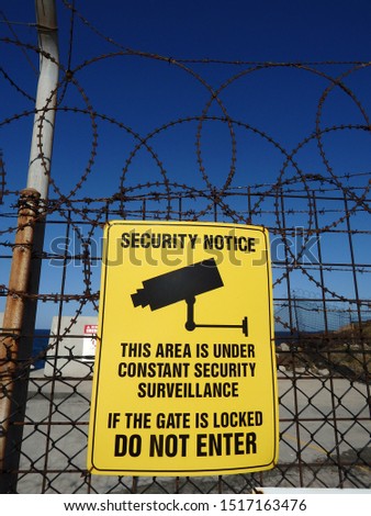 Surveillance warning sign on an outdoor high fence