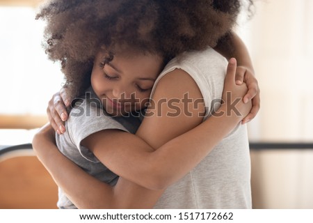 Close up image different ages girls cuddling, african little daughter closed eyes snuggled up to mother hugged her, family enjoy tender moment feeling love showing gratitude for caress and protection
