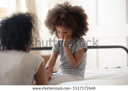 Caring african mother holds hand of sad little daughter talks gives support consoling kid, small mixed-race girl seated on bed touch cheek suffers from toothache, share mental or physical pain concept Royalty-Free Stock Photo #1517172668