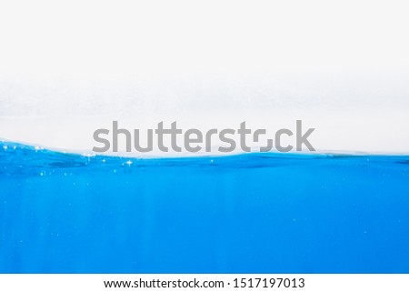 blue water surface with splash, waves and air bubbles on white background
