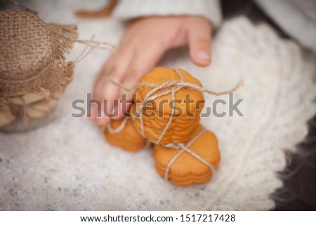 Child holding gingerl cookies  in hands. Close up photo of delicious and crunchy ginger cookies on autumn background. Baking is folded in a row on each other and tied with natural braid.