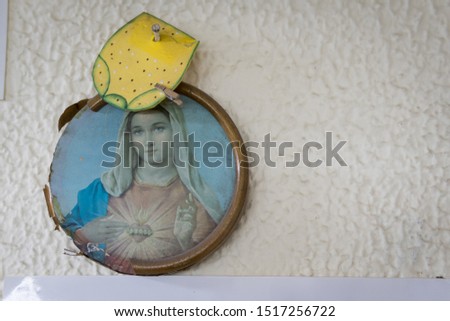 Picture of the Immaculate Heart of Virgin Mary hung to a white wall. Printed on a round wooden board. Taken in Bogota, Colombia. This image is commonly found in many houses throughout the country.