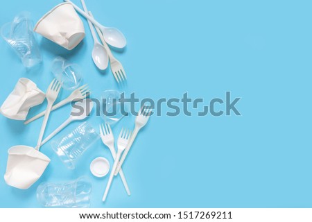 Set of plastic utensils glasses, forks, spoons on a blue background, flat lay. Concept collection of recycling plastic waste recycling. Ecology environmental care
